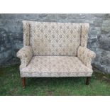 A high backed wing back two seater settee, the floral upholstery, width 53ins x height 47ins