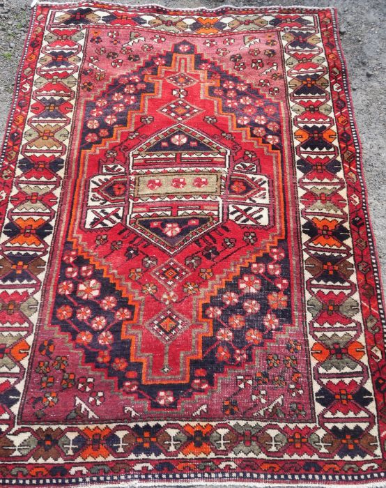 An Eastern style rug, the red ground decorated with repeating symbols, 55ins x 80ins