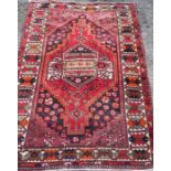 An Eastern style rug, the red ground decorated with repeating symbols, 55ins x 80ins