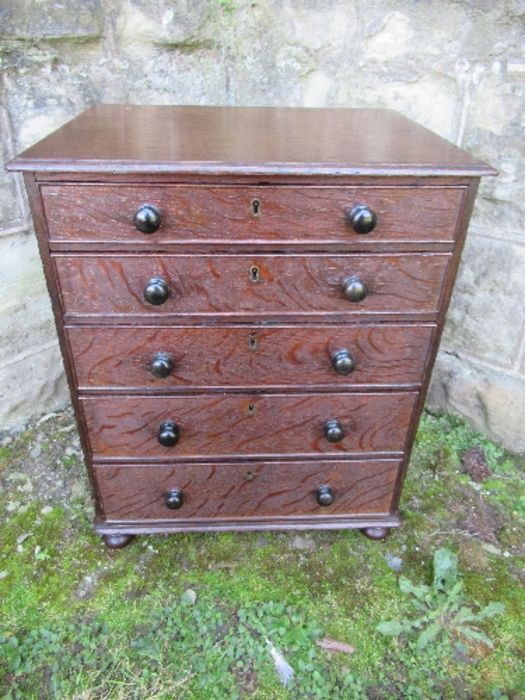 A 19th century late Georgian oak miniature chest of drawers, having five graduated drawers with