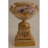 A Royal Worcester blush ivory urn shaped vase, on pierced pedestal, decorated with blue flowers,