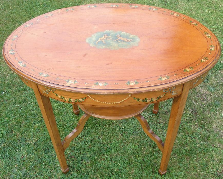 An Edwardian satinwood oval occasional table, decorated to the top and frieze with putti and