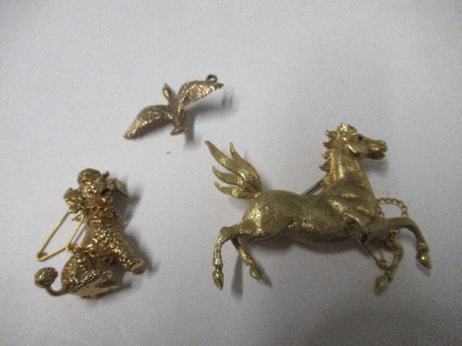 A yellow metal horse brooch, a 9ct gold duck pendant, and a 9ct gold poodle brooch, 27g gross