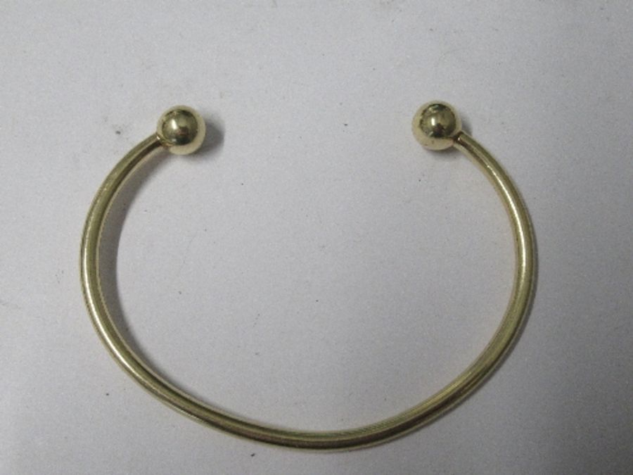 A plain torque bangle, stamped '9 KT' 12.5g gross