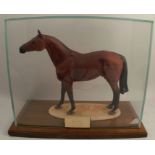 A 20th century china model, of Red Rum, in a glass display case with mahogany base, having a brass