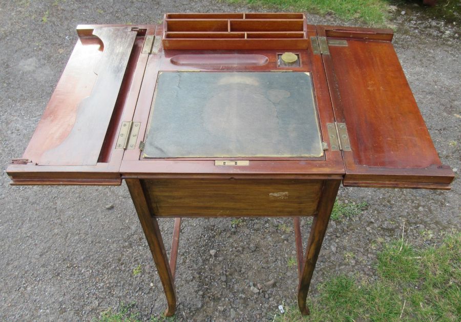 An Edwardian mahogany writing desk, the top fitted with a pair of hinged flaps, opening to reveal