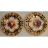 A pair of Royal Worcester plates, decorated with central panels of fruit, to a gilt blue gilded