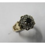 A 9 carat gold sapphire and diamond cluster ring, the round cut stone enclosed by single cuts,