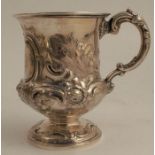 A Victorian silver mug, with embossed decoration and monogram, raised on a circular pedestal foot,
