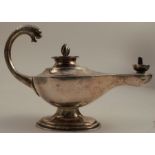 A silver Aladdin's lamp oil lamp, with mask to the handle, raised on an oval pedestal foot,