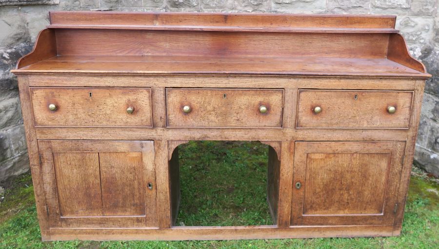 An antique oak Welsh sideboard, with three drawers to the frieze, above cupboard doors to each side,