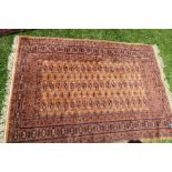 A modern Eastern design rug, decorated with repeating symbols to a gold ground, 50ins x 70ins