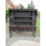 An oak dresser, with close boarded rack back, fitted with cupboards, the base with three drawers,