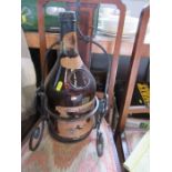 A large Cognac bottle in a wrought iron stand, bearing label Salignac, height 23.5ins