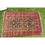 An Eastern prayer rug, the field decorated with repeating symbols, the borders with red ground,