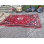 An Eastern design red ground rug, 67ins x 114ins