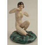 A continental porcelain figure, of a naked kneeling female on green cushion, height 3.5ins