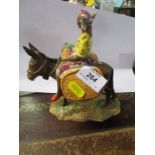A Beswick figure holding fruit, sitting astride a donkey with carrying baskets