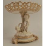 A Royal Worcester comport, with pierced shaped edge, raised on a column with two putti to a circular