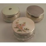 Two glass dressing table pots, with hallmarked silver covers, one decorated with enamel, together