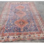 An Antique rug, decorated with three lozenges to a blue field, with triple border, 116ins x 84ins