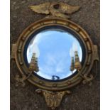 A gilt framed convex wall mirror, with eagle to the top, having a pair of scroll arms with lights,