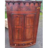 A 19th century mahogany barrel fronted corner cabinet, fitted with a pair of doors revealing shelves