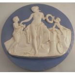 A 19th century English pottery wall plaque, embossed with three Classical figures to a blue
