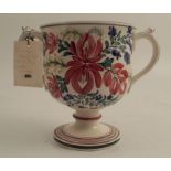 A 19th century pottery pedestal loving mug, decorated with flowers, the interior having three frogs,