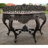 An Antique oak side table, of shaped D form, heavily carved with flowers and leaves, on scroll