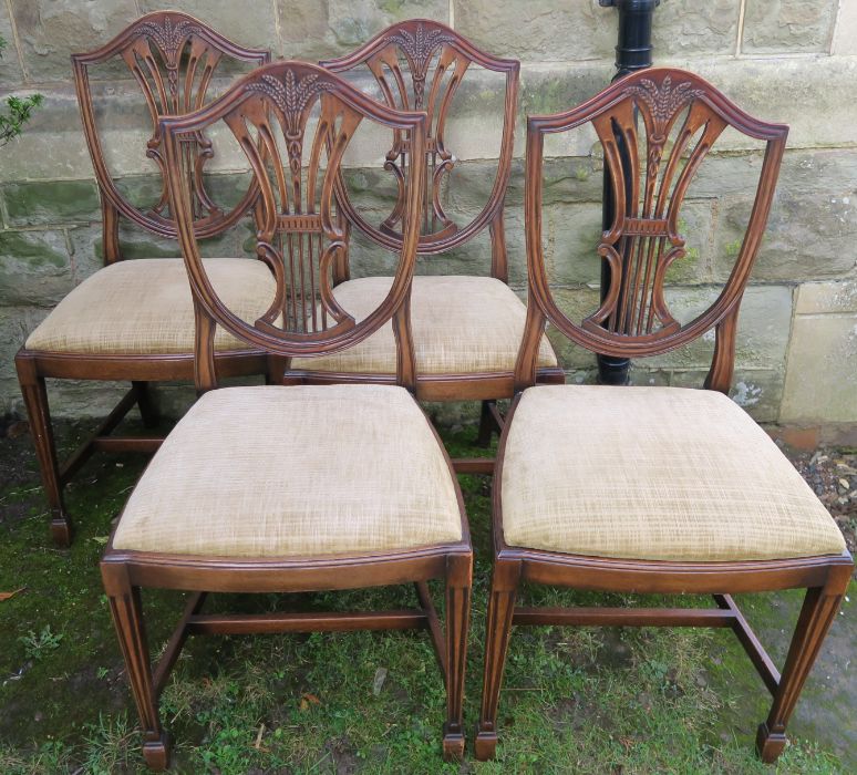 A set of four reproduction mahogany dining chairs, with carved shield backs and drop in seats