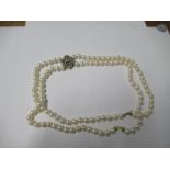 A two row uniform cultured pearl necklace to a diamond set frontispiece, the 57 and 54 pearls of