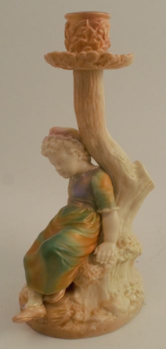 A Hadleys Worcester blush ivory and shot silk candle stick, formed as a child seated by a tree,