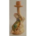 A Hadleys Worcester blush ivory and shot silk candle stick, formed as a child seated by a tree,