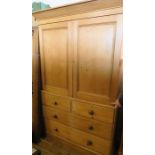 A pine linen press, having panelled doors opening to reveal pull out trays, over two short drawers
