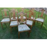 A set of eight Arts and Crafts style dining chairs, having arched back and tulip pierced cut splats,