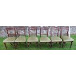 A set of six Edwardian oak dining chairs, each having a carved crested rail, below a spindle