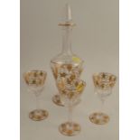 A glass decanter, with gilt vine decoration, together with three glasses