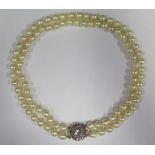 A Twin Strand Pearl Choker with a rose cut diamond and ruby clasp, the central stone with a