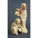 An Antique Oriental Ivory Okimono of a lady with kettle and kneeling man feeding a tortoise from a
