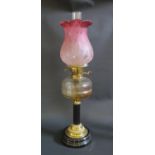 An Antique Oil Burner with slice cut glass reservoir and cranberry glass shade, 62.5cm to top of