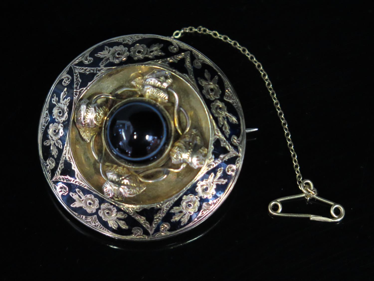 A Victorian Gold and Black Enamel Memorial Brooch set with a central circular cabochon banded