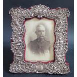 A Victorian Silver Mounted and Plush Photograph Frame decorated with putti and scrolling foliate