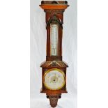A late 19th century carved walnut wall mounted aneroid barometer with thermometer,