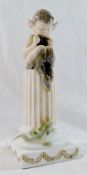 A Royal Copenhagen porcelain figure of a fawn seated on a pillar playing the pipes,