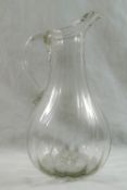 An 18th century French glass jug with moulded vertical ribs and folded rim,