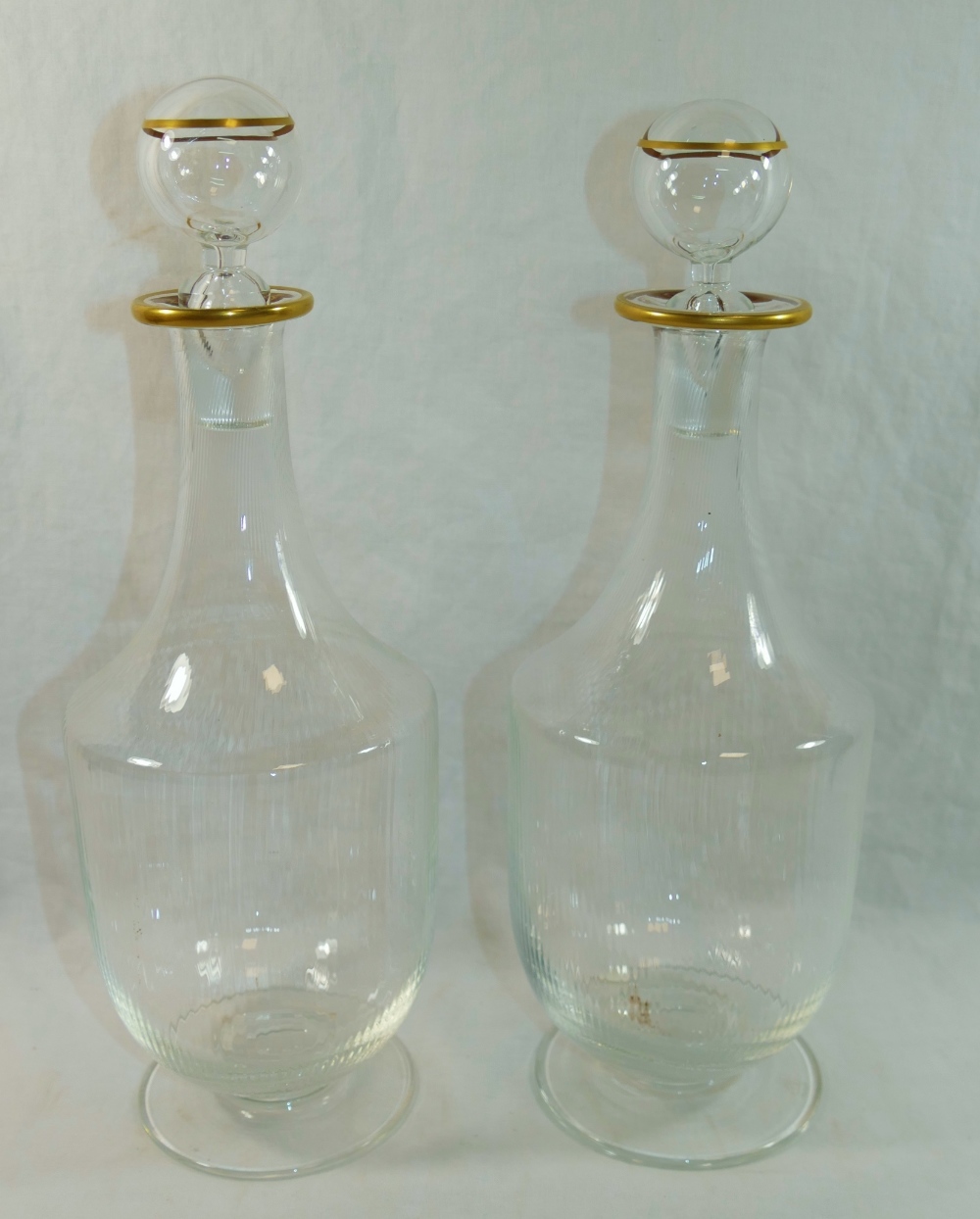 A pair of Murano clear glass decanters with gilt rims,