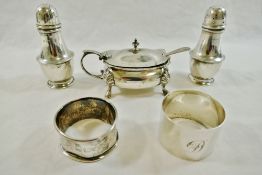 A silver three piece cruet set comprised of a mustard pot with spoon and two pepperettes,