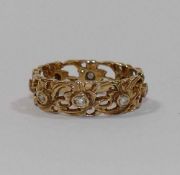 An orante yellow metal diamond set pierced floral band, stamped '14K',