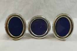 A pair of small Italian oval photograph frames and a circular similar photograph frame,